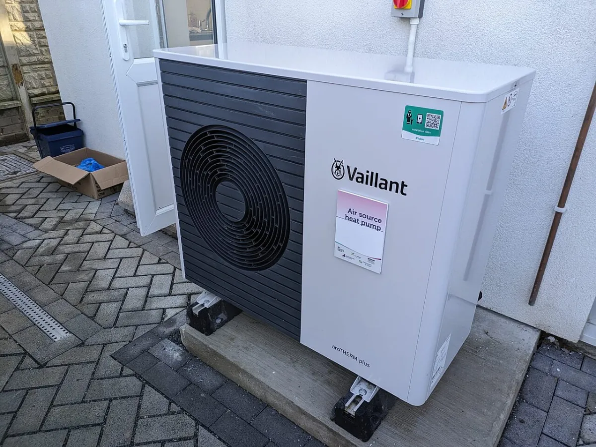 Unité extérieure de pompe à chaleur air-eau contre la façade d’une maison