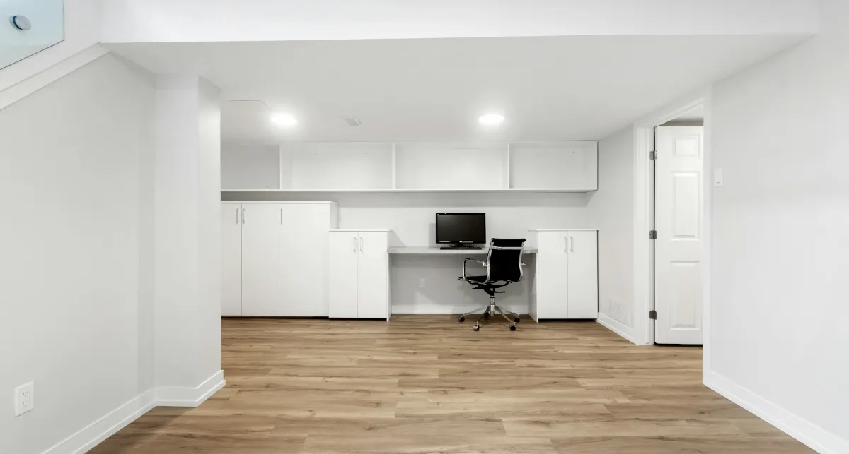 Pièce aménagée aux murs blancs avec sol stratifié, spots encastrés et bureau intégré
